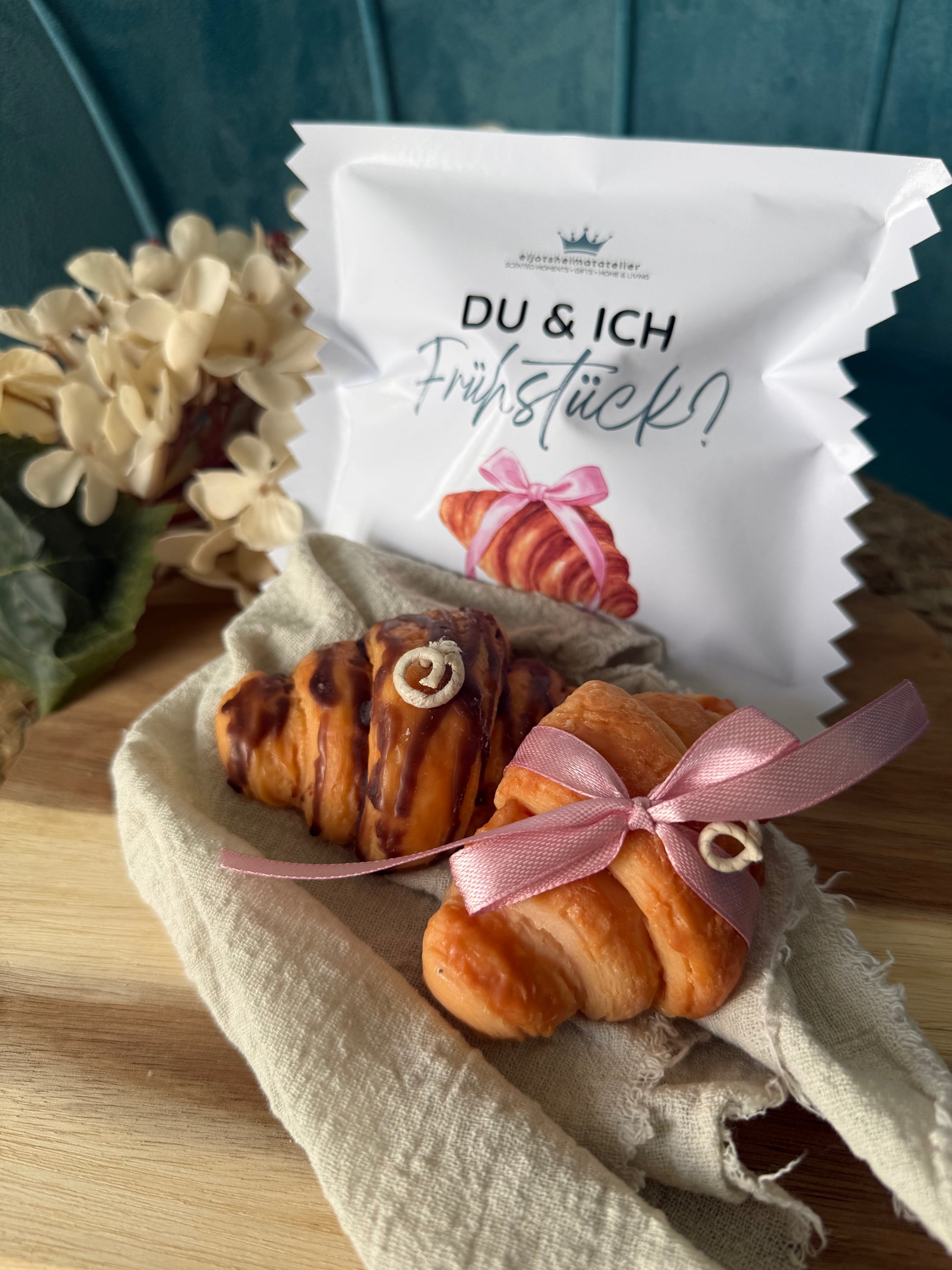 Detailreiche Croissant-Duftkerze in realistischer Gebäckoptik mit goldbrauner Oberfläche und geschichteten Butterteig-Details. Die handgegossene Kerze erinnert an ein frisch gebackenes französisches Croissant aus einer Patisserie und verströmt einen warmen, süßen Duft. Stilvoll dekoriert auf hellem Untergrund im minimalistischen Café- und Interior-Stil.
